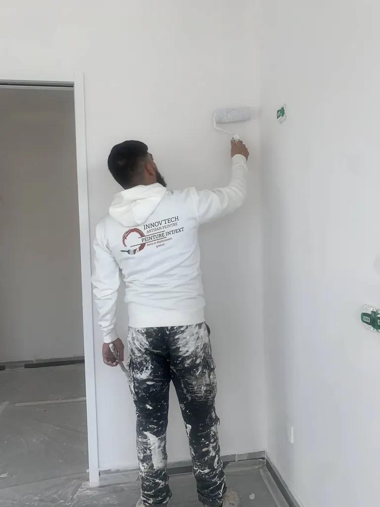 Peintre appliquant une peinture blanche au rouleau